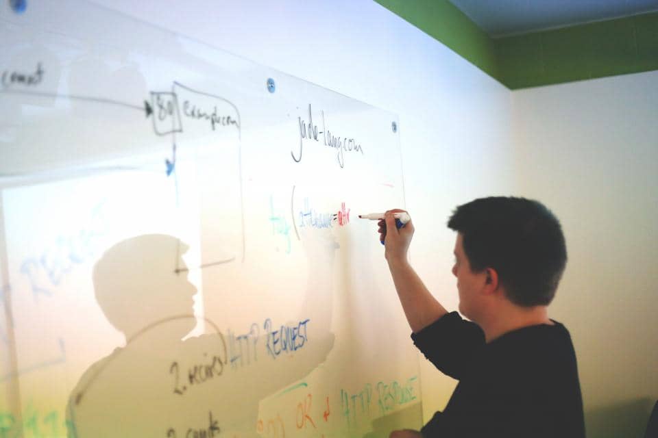 man writing online business launch plans on dry erase board